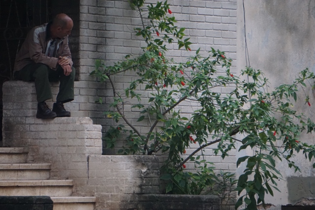 Cuban man sitting on a stoop. 